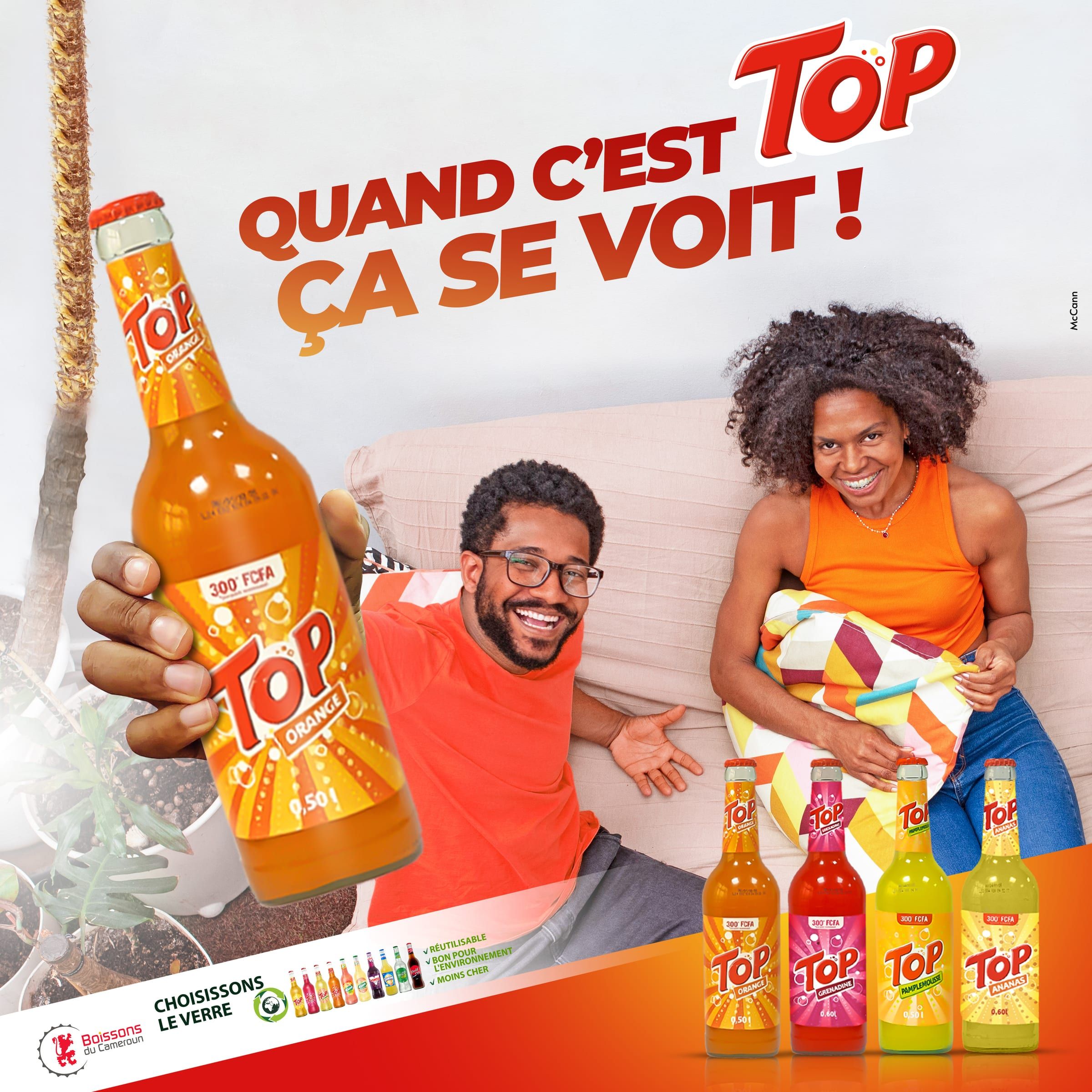 Visuel Top « Quand c'est Top, ça se voit ! » : un couple rit sur un canapé, une main tend une bouteille de Top Orange, la gamme au premier plan.