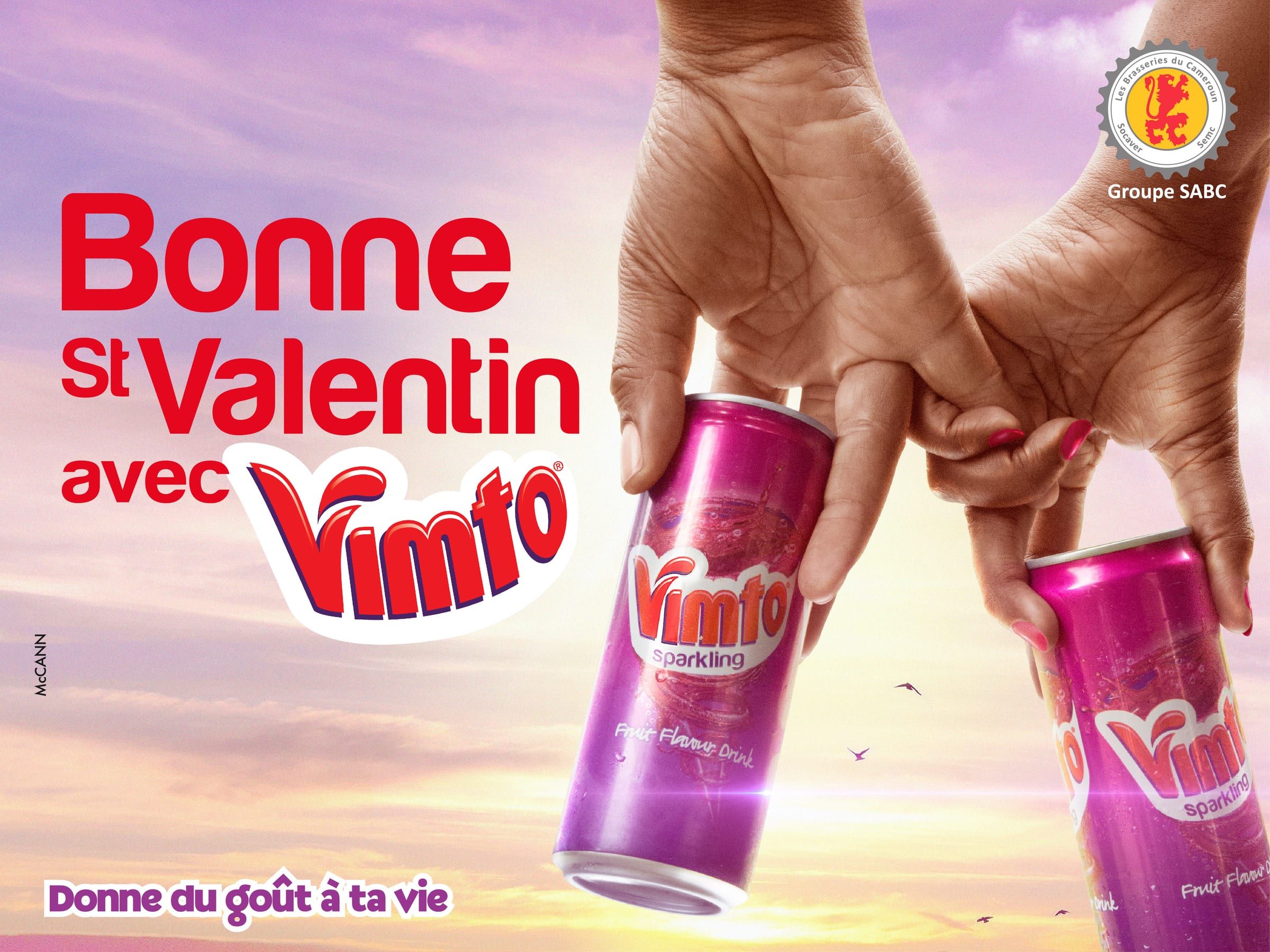 Affiche 4x3 « Bonne St Valentin avec Vimto » : deux mains entrelacent leurs doigts en tenant chacune une canette de Vimto Sparkling, sur un ciel rose.